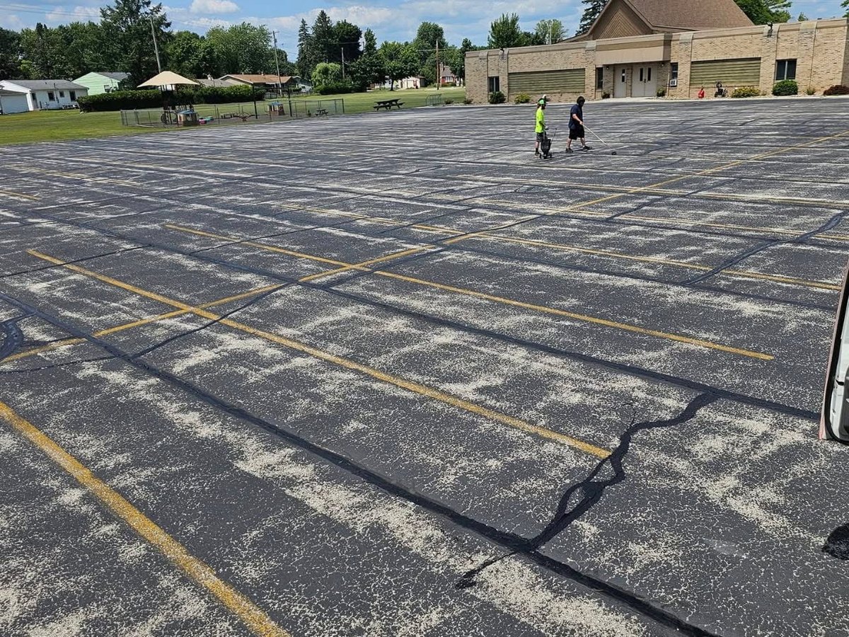 Before, a faded and worn parking lot, stripes barely visible, before sealcoating