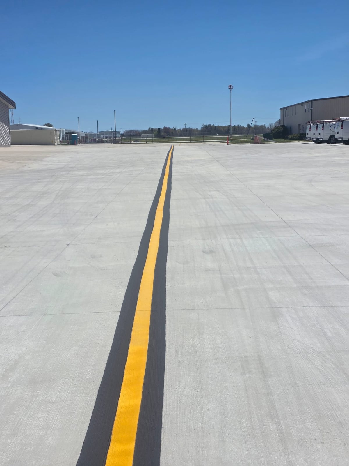 a wide airfield apron with a crisp yellow centerline running to the horizon by Draki Enterprises in Wisconsin