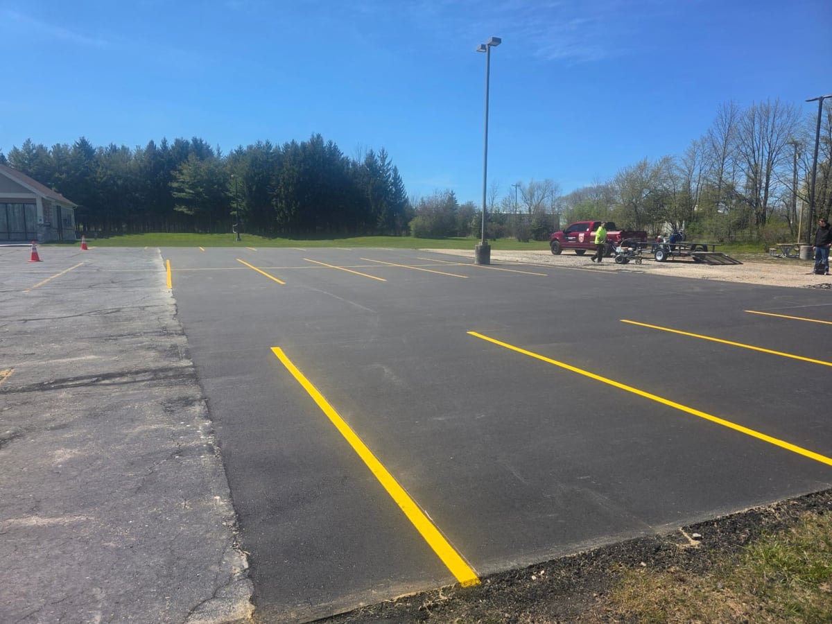 a broad airfield apron with fresh yellow striping and the crew working near the hangars by Draki Enterprises in Wisconsin