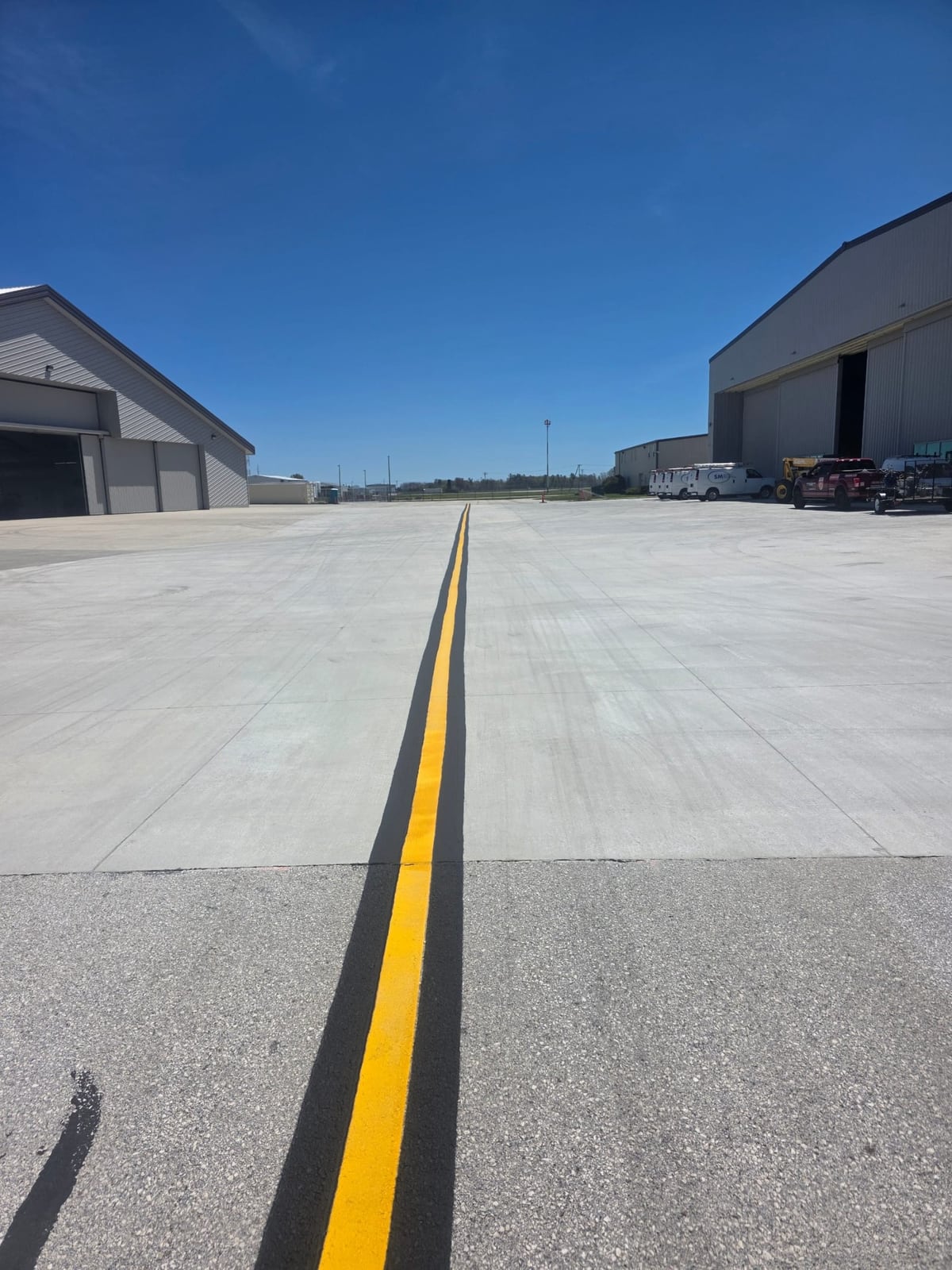 a wide open airfield surface with a single yellow centerline reaching the horizon by Draki Enterprises in Wisconsin