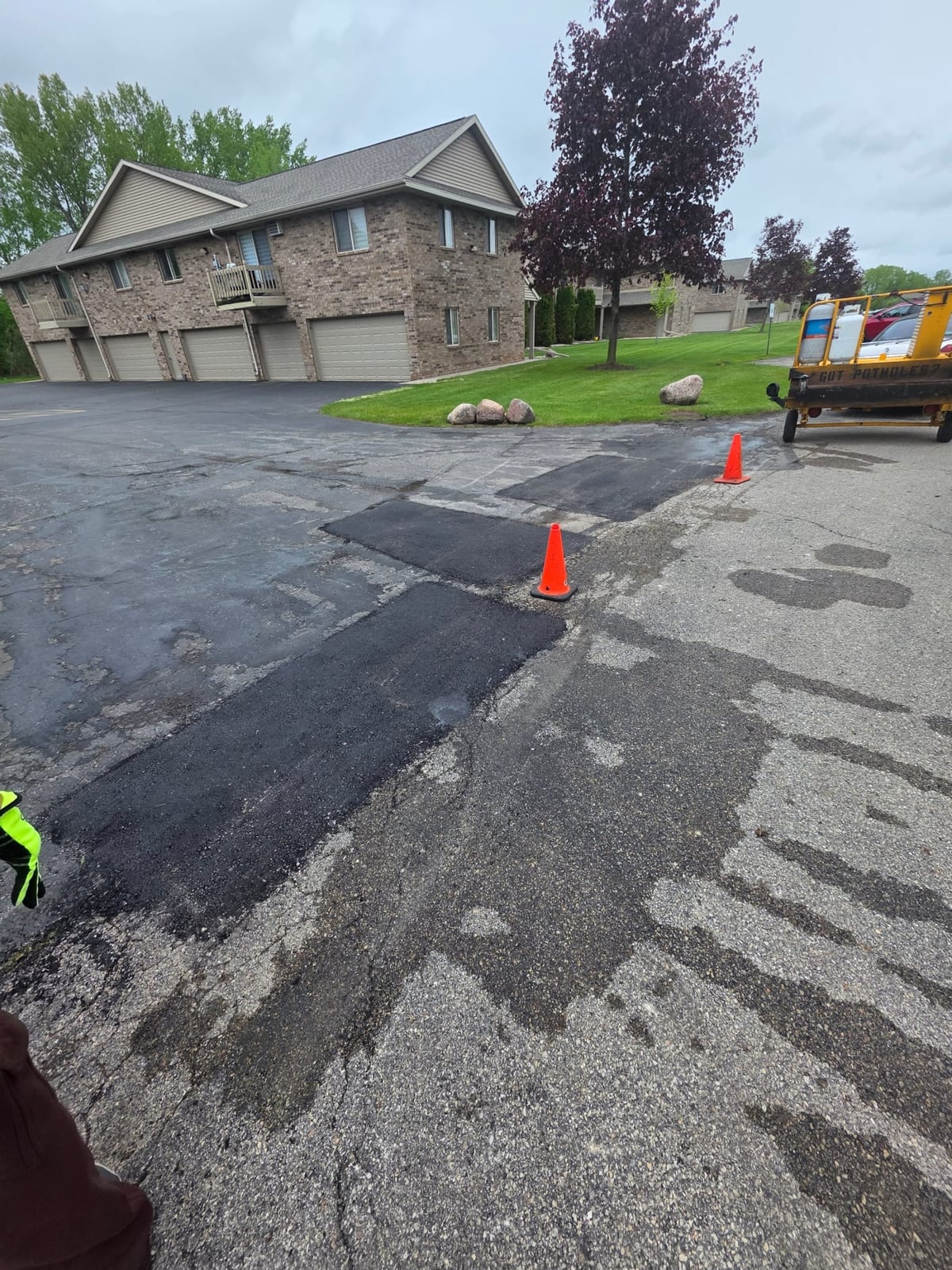 a fresh black asphalt patch laid into a repaired section of a parking lot by Draki Enterprises in Wisconsin