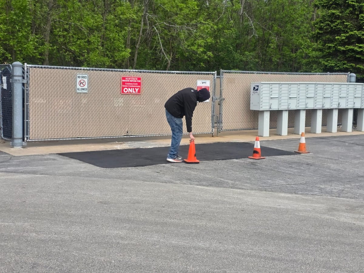 a self-storage facility with a worker and cones on a freshly sealed drive by Draki Enterprises in Wisconsin
