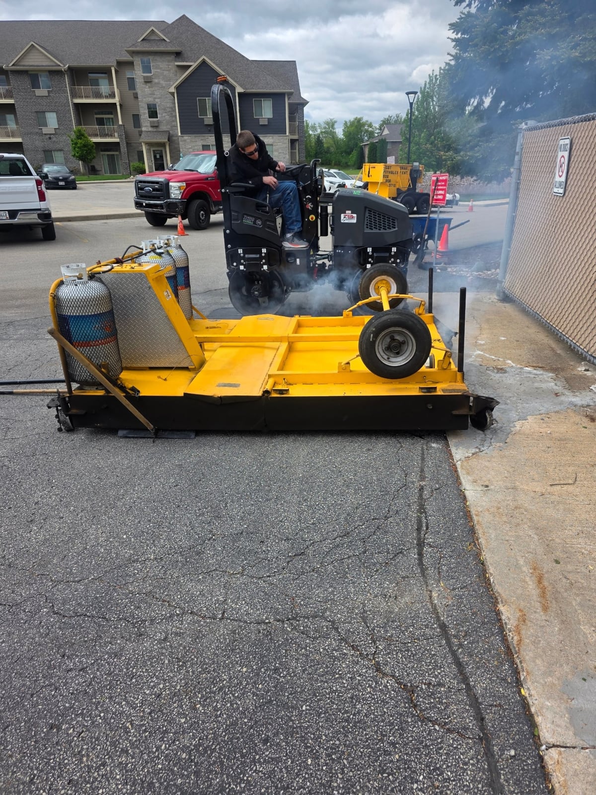 a yellow infrared asphalt heater unit set up on a lot with a work truck by Draki Enterprises in Wisconsin