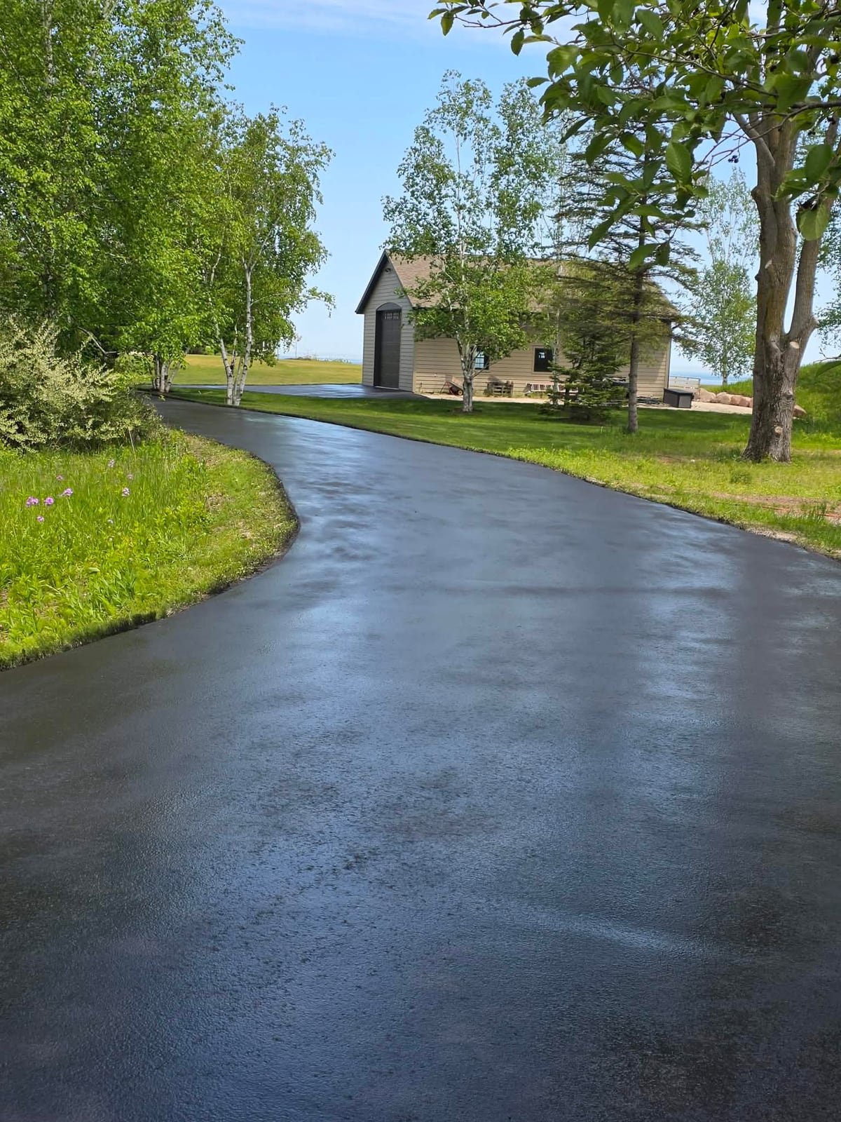 a residential driveway sealed to a deep black, curving up to a house by Draki Enterprises in Wisconsin