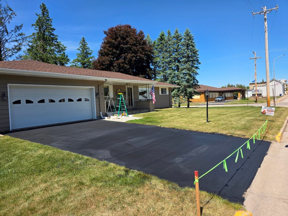 a residential home with an attached garage and a freshly sealed black driveway by Draki Enterprises in Wisconsin