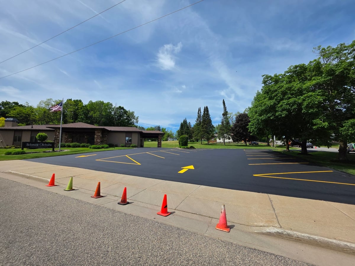 a parking lot mid-striping with cones and fresh yellow directional arrows by Draki Enterprises in Wisconsin