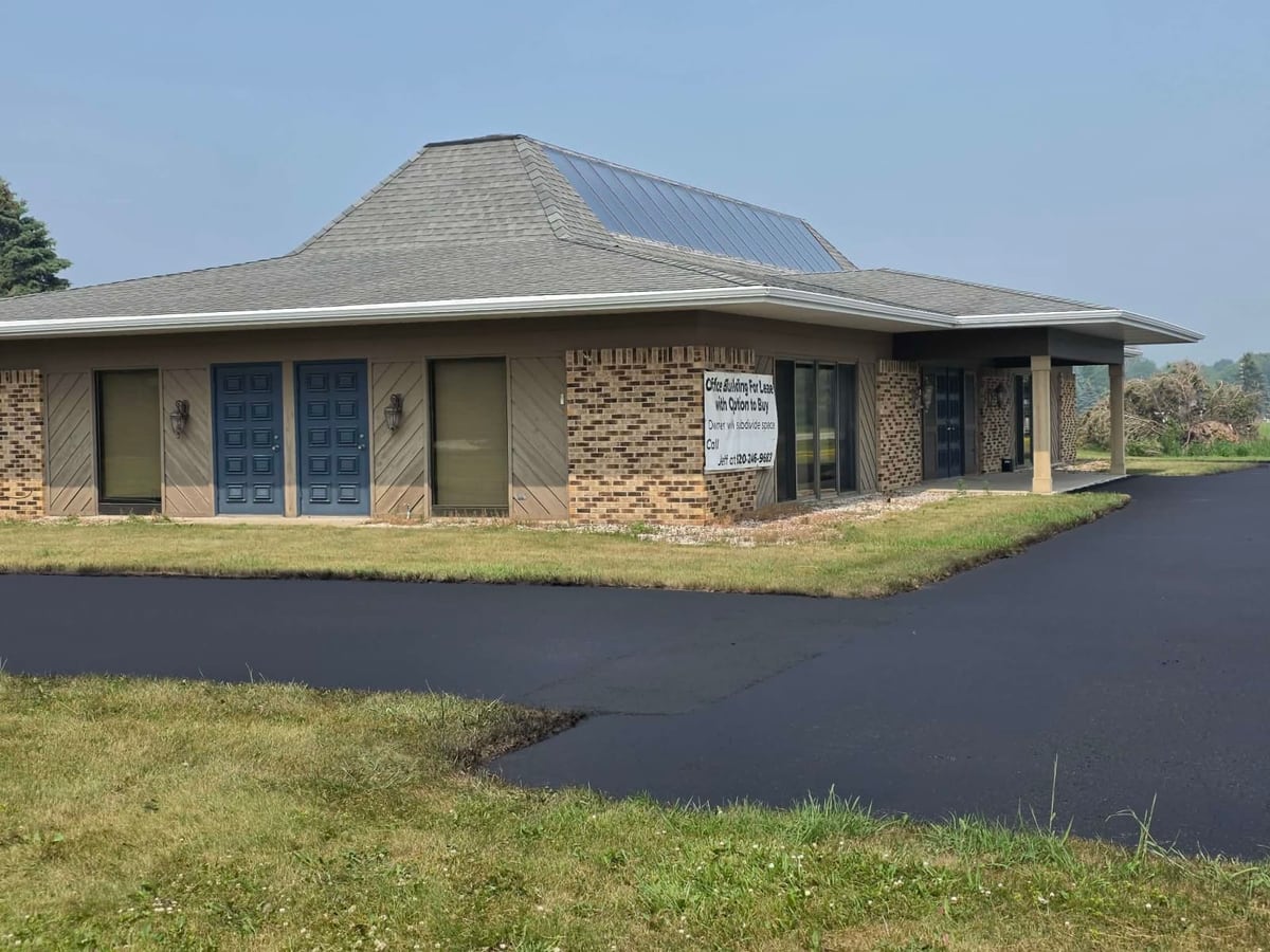 a stone office building with a freshly sealed and striped parking lot by Draki Enterprises in Wisconsin